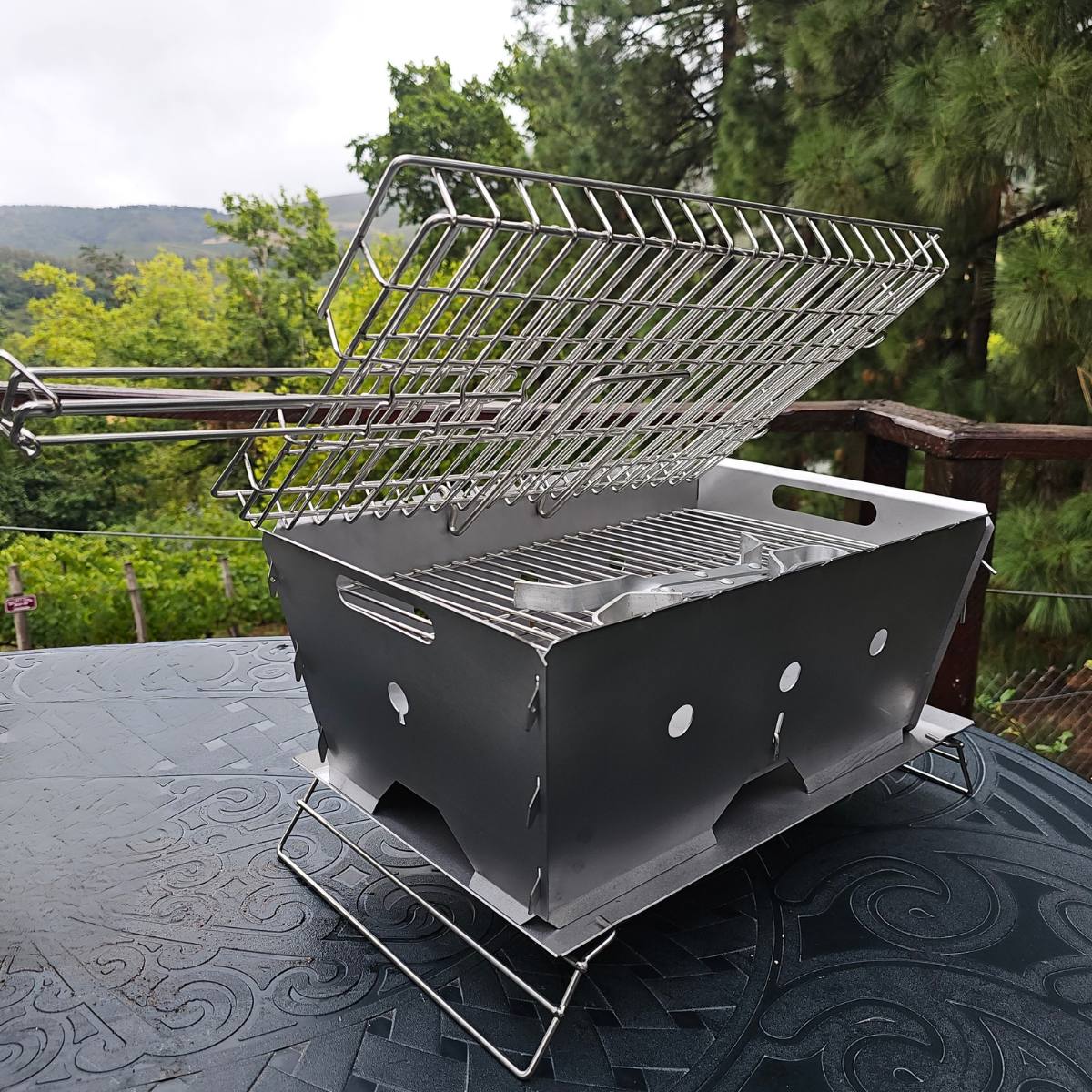 Flat Pack Deluxe Long Braai stainless steel portable braai with double grid open on outdoor table